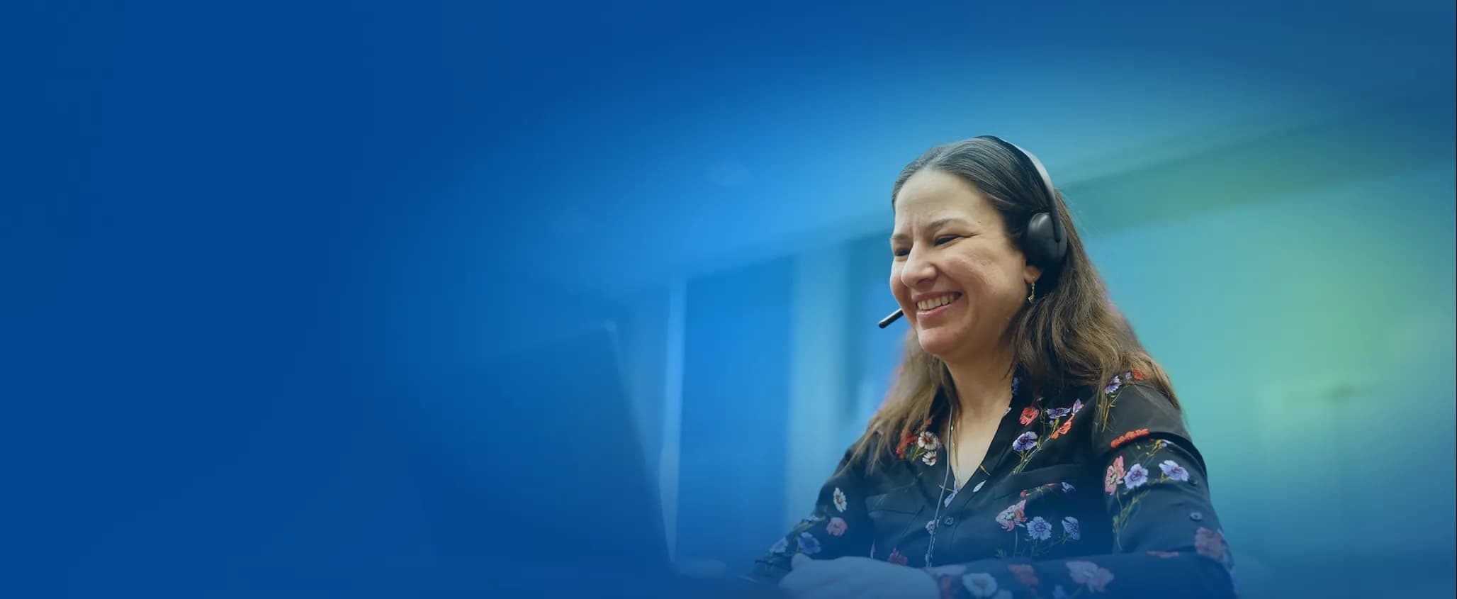 Women with headphones smiling and working at a computer.
